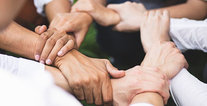 several hands grip each other in a circle