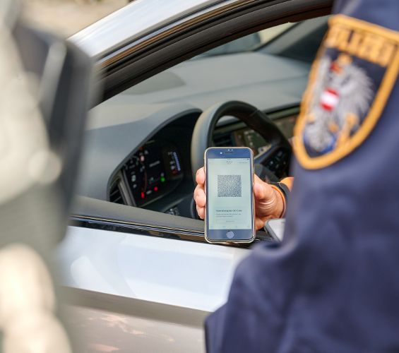 Person in a car has mobile in hand to show digital drivers licence or digital car registration certificate