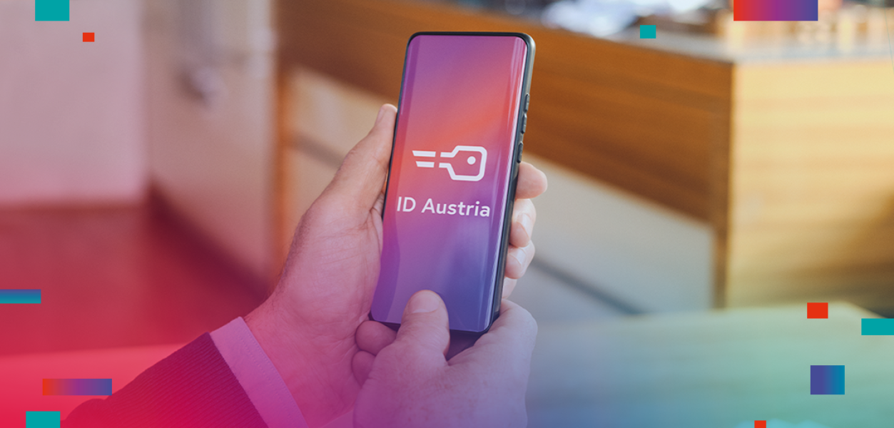 Smartphone wird von einer Männerhand gehalten. Auf dem Smartphone ist das Schlüssellogo der ID Austria und der Schriftzug ID Austria. Daher ist eine Küchentheke zu sehen.